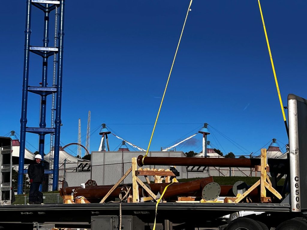 Crane lifting structural components from flatbed trailer